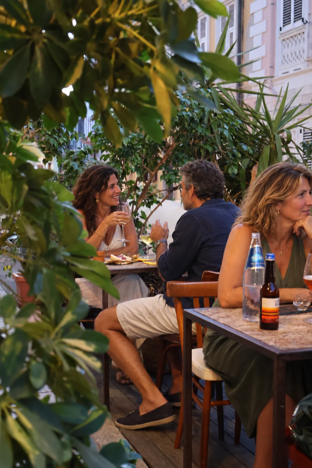 Il dehors di U Magazin tra le piante, con ospiti ai tavoli alla sera